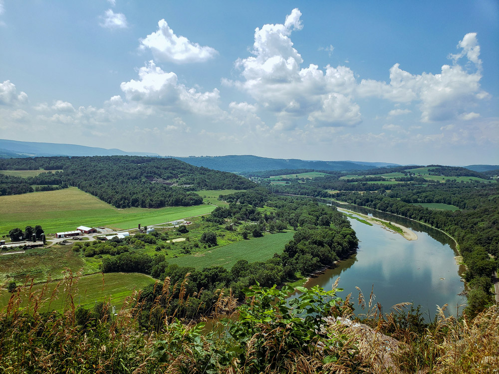 A wide river winding through a green rural landscape under a bright sky, representing local Rights of Nature protections in Pennsylvania, USA.